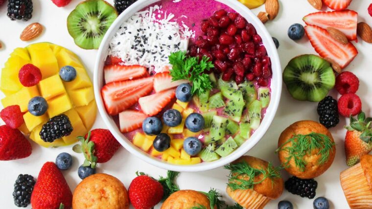Vibrant smoothie bowl topped with assorted fresh fruits and muffins, perfect for a healthy snack.